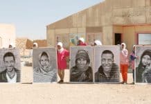 En gruppe saharawiske flygtninge holder store portrætter op under FN's generalsekretærs besøg i Smara-flygtningelejren uden for Tindouf i Algeriet i 2016. FN Foto/Evan Schneider