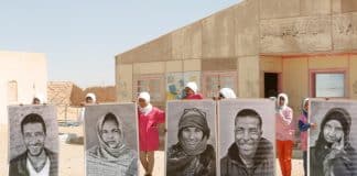 En gruppe saharawiske flygtninge holder store portrætter op under FN's generalsekretærs besøg i Smara-flygtningelejren uden for Tindouf i Algeriet i 2016. FN Foto/Evan Schneider