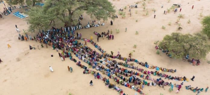 © UNHCR/Colin Delfosse- Menschen, die durch den Konflikt im Sudan vertrieben wurden, stehen bei ihrer Ankunft im Tschad für Hilfe an.