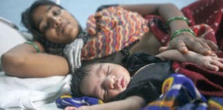 A two day old child sleeps next to its mother at a maternity ward in Rajasthan, India.