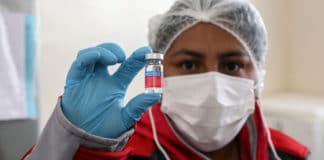 A nurse in Boliva holds up a dose of flu vaccination.