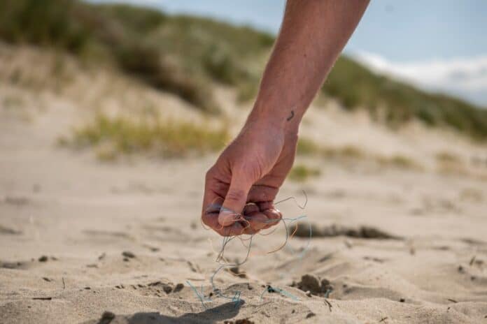 Hand in the sand picking up trash