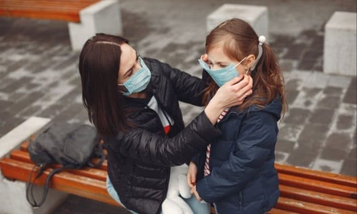 Mother helping put her mask on