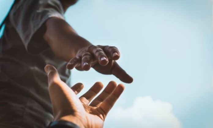 Two people's hands trying to reach each other