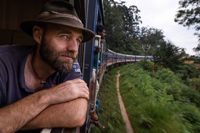 A man looking out from a train window in an exotic destination