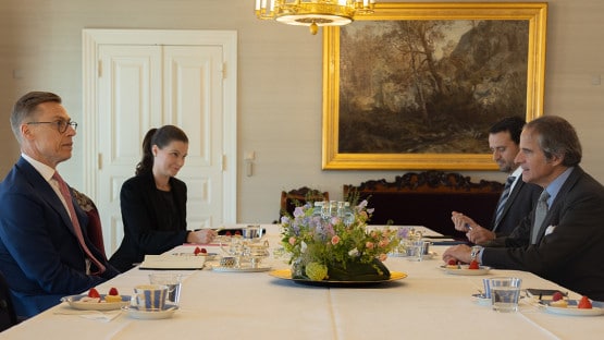 Three men and one woman in formal clothing around a table