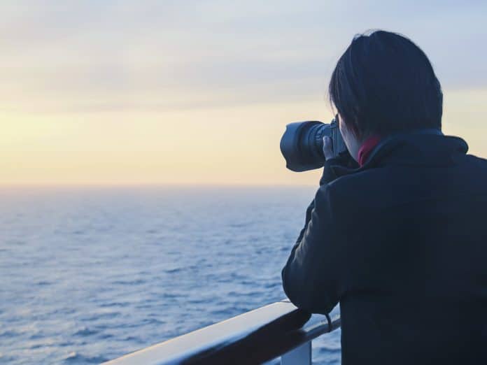 Person taking a photograph from a ship at sea. IMO website © IMO