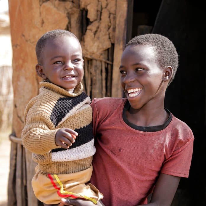 A child holding a smaller child, both happy