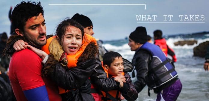 Un enfant dans les bras d'un homme au bord de la mer. Ce sont des refugies qui viennent d'acoster