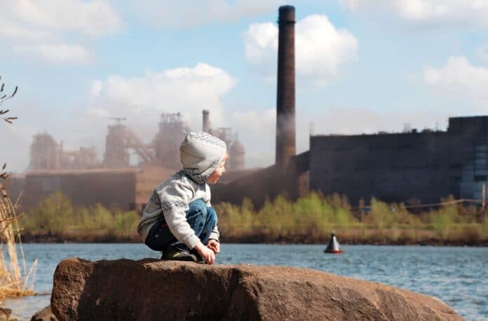 Un enfant jouant dans une zone industrielle contribuant à la pollution de l’air