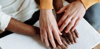 Personnes handicapées - Les mains de deux personnes l’une aidant l’autre à lire le braille