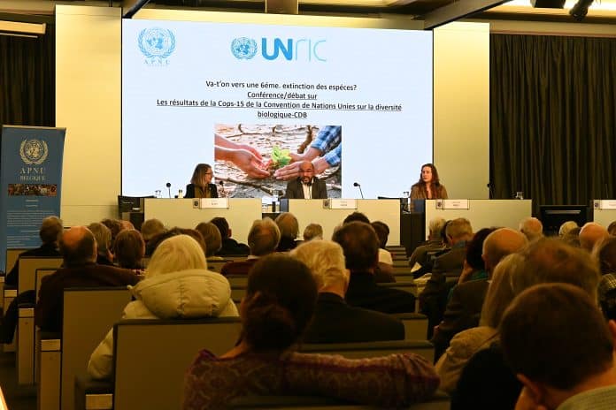 Conférence APNU/UNRIC sur les résultats de la COP15, les deux intervenants : représentant de l'UNEP et du WWF, et la directrice d'UNRIC assis derrière leur pupitre sur la scène face à l'audience.