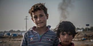 deux enfants face caméra devant un paysage dévasté