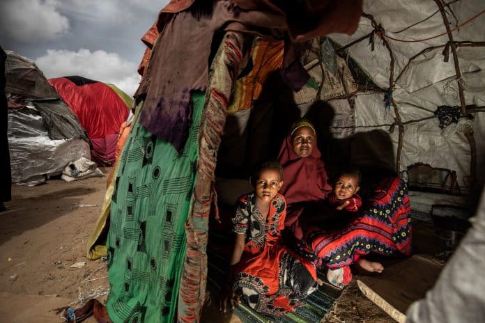 Une mère et ses enfants posent pour une photo dans leur abri temporaire dans un camp pour personnes déplacées. Somalie 2022