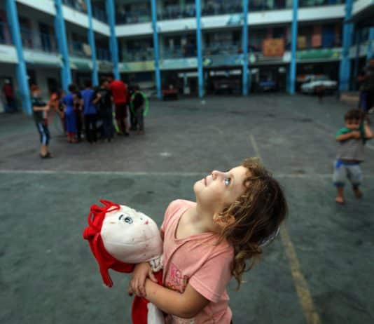 Aya, une fillette de 5 ans, serrant sa poupée pour apaiser sa peur, regarde le ciel de Gaza rempli d'avions de guerre depuis l'intérieur d'une école de l'UNRWA dans la bande de Gaza.