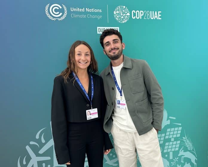 Victoria et Johan posant devant une affiche de la COP28 à Dubaï.