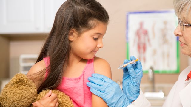 Infirmière qui vaccine une petite fille dans un cabinet médical.