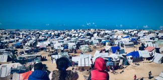 Trois enfants sur une colline face à une camp de déplacés