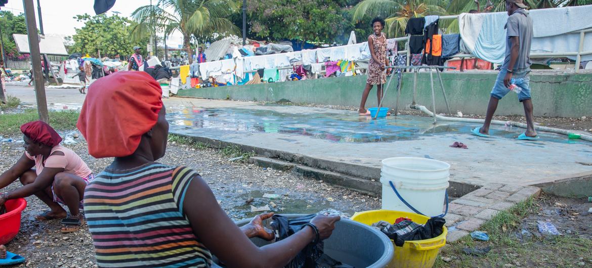 Kona sem flúð hefur heimili sitt þvær þvott í almenningsgarði í Port-au-Prince.