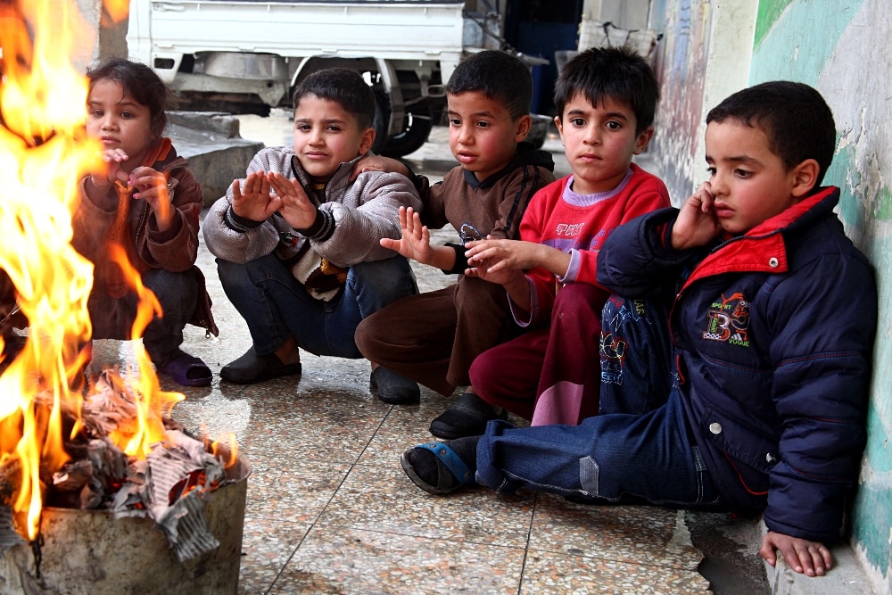 Flóttabörn reyna að halda á sér hita í skýli á vegum UNRWA