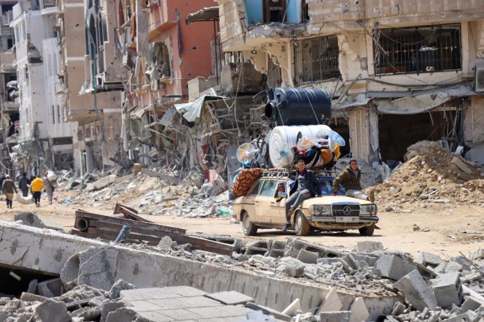 Khan Younis á Gasasvæðinu 10.apríl 2024. Mynd: UNOCHA/Themba Linden Widespread destruction in Khan Younis. A UN team (OCHA, UNRWA, WHO, WFP, UNMAS, and UNFPA) visited Khan Younis on 10 April following the withdrawal of Israeli troops from that area. They report profound destruction: every building the team visited and most of the buildings observed were damaged, and paved roads had been reduced to dirt tracks. Streets and public spaces are also marred with unexploded ordnance, posing severe risks to civilians. The team recorded unexploded 1,000-pound bombs lying on main intersections and inside schools. Returnees and a handful of people who remained through the fighting told the team that there they faced dire shortages of food and water, compounded by the loss of critical healthcare services due to the destruction of Nasser and Al Amal hospitals. © UNOCHA/Themba Linden