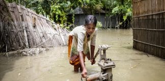 Ung stúlka reynir að pumpa vatni á flóðasvæði í Bangladesh 2016