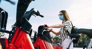 Woman wearing protective face mask taking a rented electric bicycle. Taking an electric bike. Electric bicycle rental.