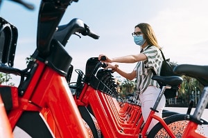 Woman wearing protective face mask taking a rented electric bicycle. Taking an electric bike. Electric bicycle rental.