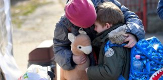 Una bambina ucraina consola suo fratello di sei anni mentre si preparano a lasciare un centro sostenuto dall'UNICEF in Romania per la loro prossima destinazione.