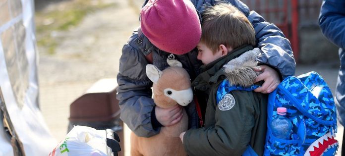 Una bambina ucraina consola suo fratello di sei anni mentre si preparano a lasciare un centro sostenuto dall'UNICEF in Romania per la loro prossima destinazione.