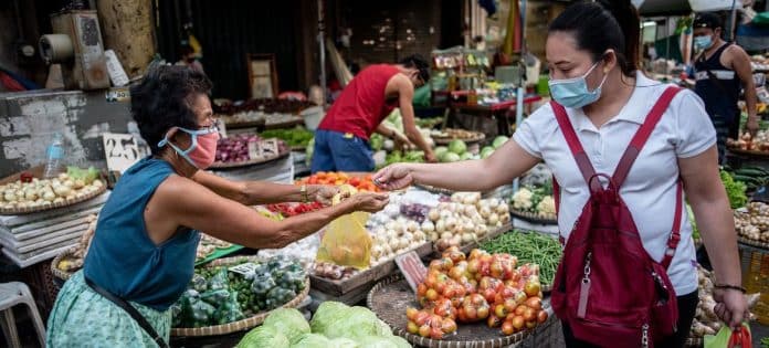 IMF:Lisa Marie David A vegetable vendor serves a customer at a market in Manila, Philippines.