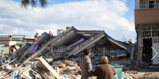 A man and woman look at a collapsed building in Islahyia, Türkiye, on 7 February 2023