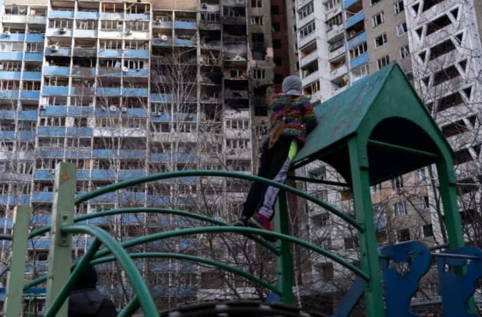 Una bambina guarda gli appartamenti bruciati, in piedi su un campo da gioco nel cortile del condominio che ha subito un bombardamento la mattina del 7 febbraio 2024, a Kiev, Ucraina.