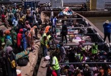 Hjelpearbeidere hjelper hjemvendte fra Sudan i havnen i Renk i Sør-Sudan, der de skal gå om bord i en båt som skal ta rundt 600 passasjerer til Malakal i løpet av to og en halv dag, før de reiser videre til andre deler av landet. Mai 2024. Foto; OCHA/Liz Loh-Taylor