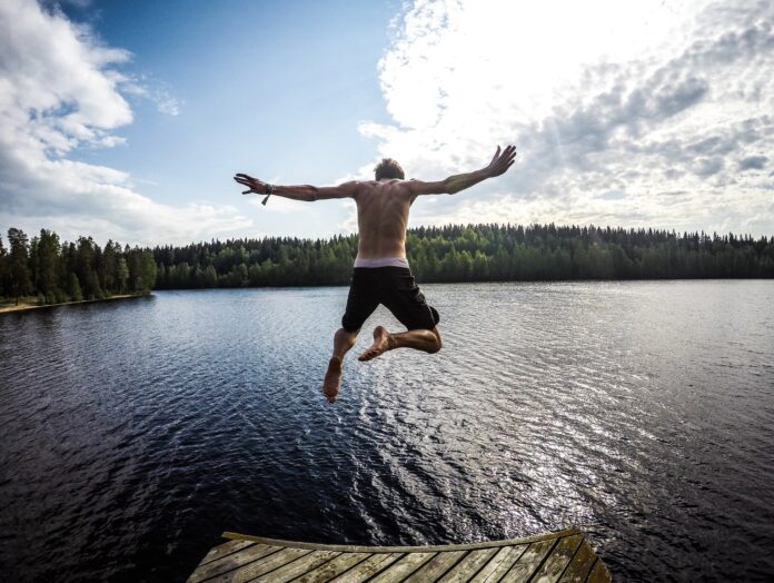 man som hoppar i vattnet, solig dag, sommar, sjö